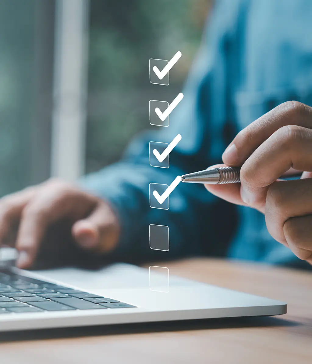 Mann vor Laptop hakt Checkliste ab